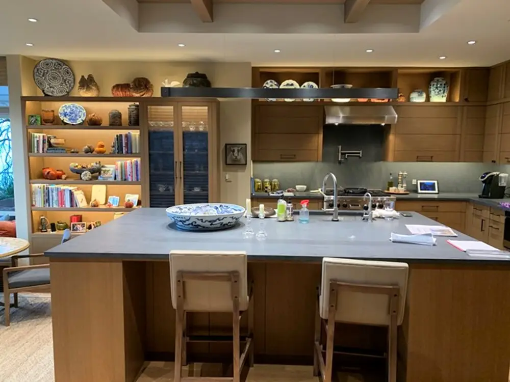 Open kitchen with oversized island, custom cabinetry, professional cooking area, and built-in display shelving.