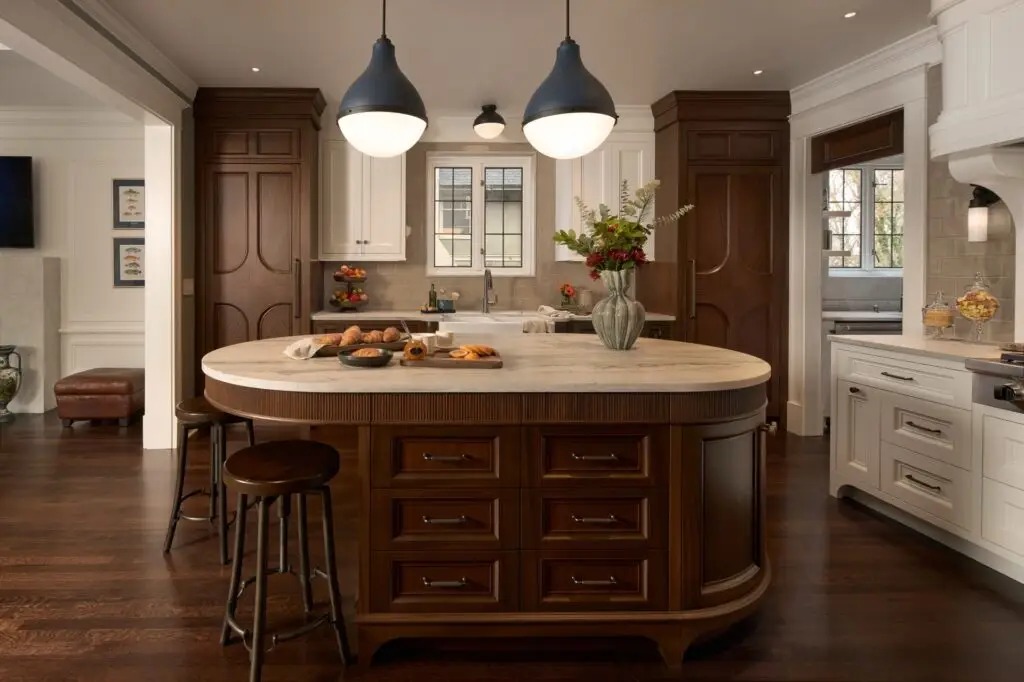 Open kitchen with large central island, custom wood cabinetry, pendant lighting, and adjoining dining space.