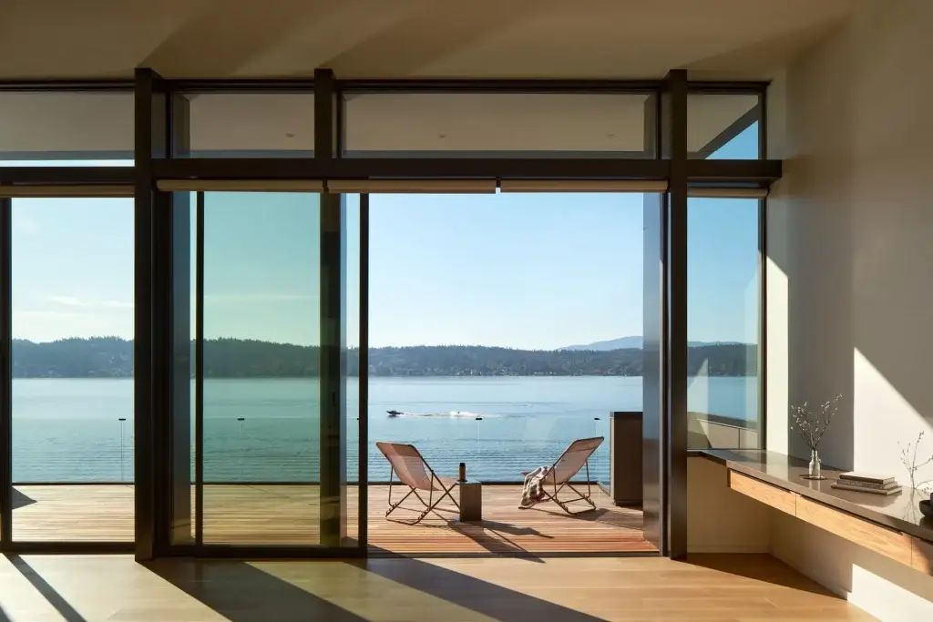 Contemporary living room with floor-to-ceiling sliding glass doors opening to a terrace overlooking the lake.